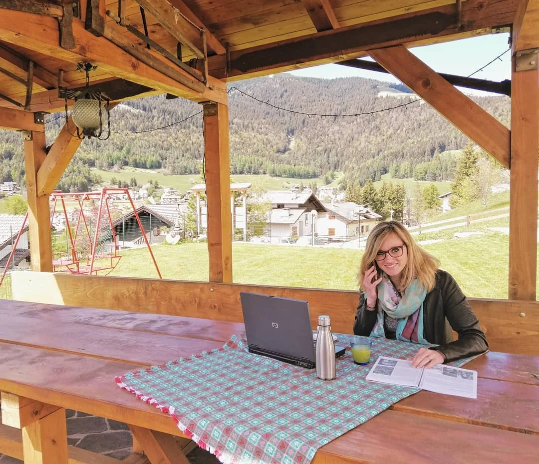 Un'ospite lavora al portatile sotto il gazebo, con la valle davanti