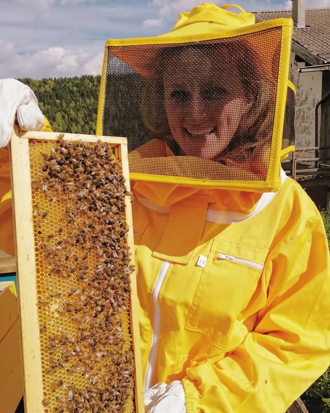 Daniela in tuta da apicoltrice con un telaio pieno di api