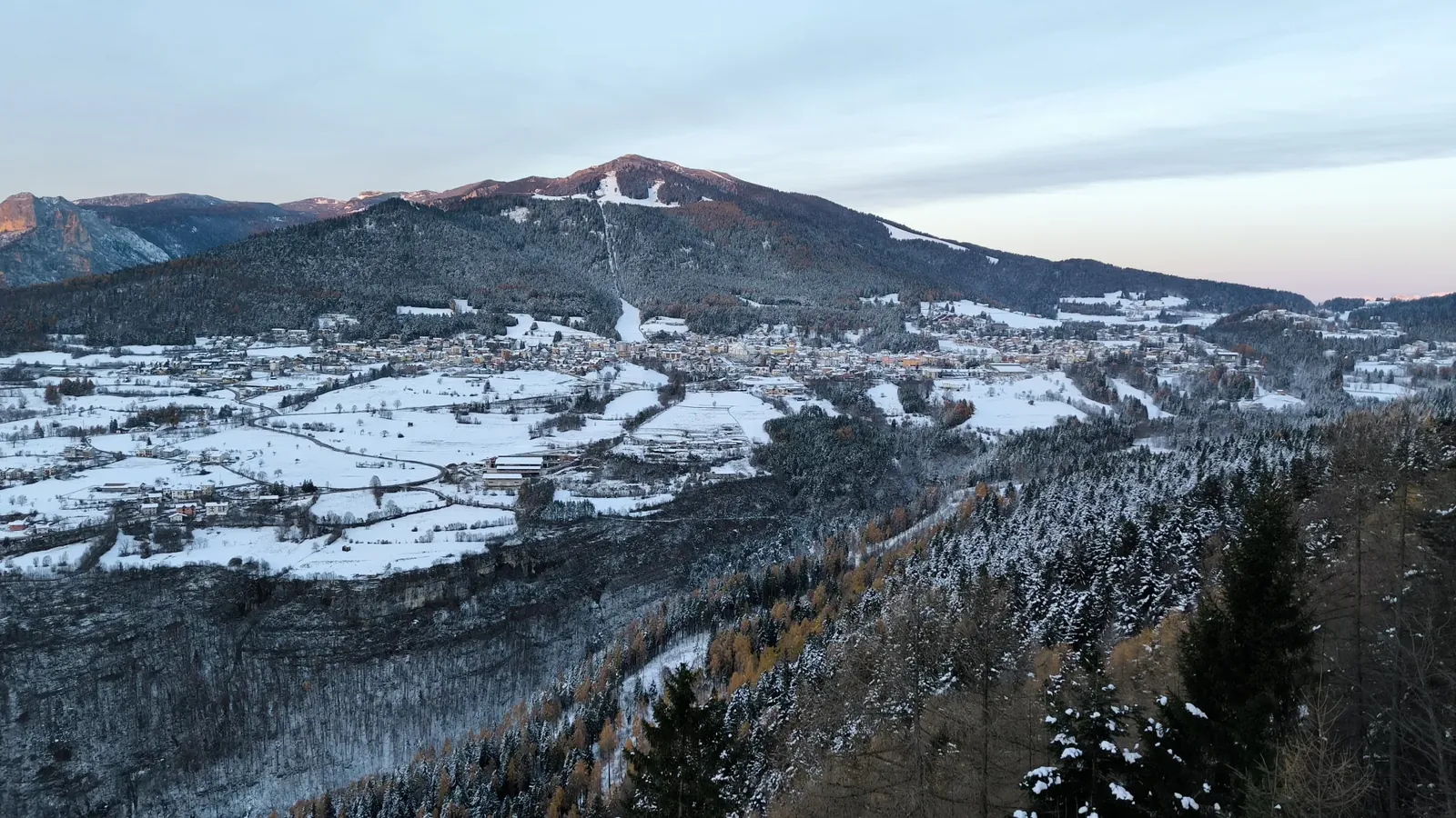 Folgaria innevata al tramonto, con la luce rosata che accende la cima del Monte Cornetto