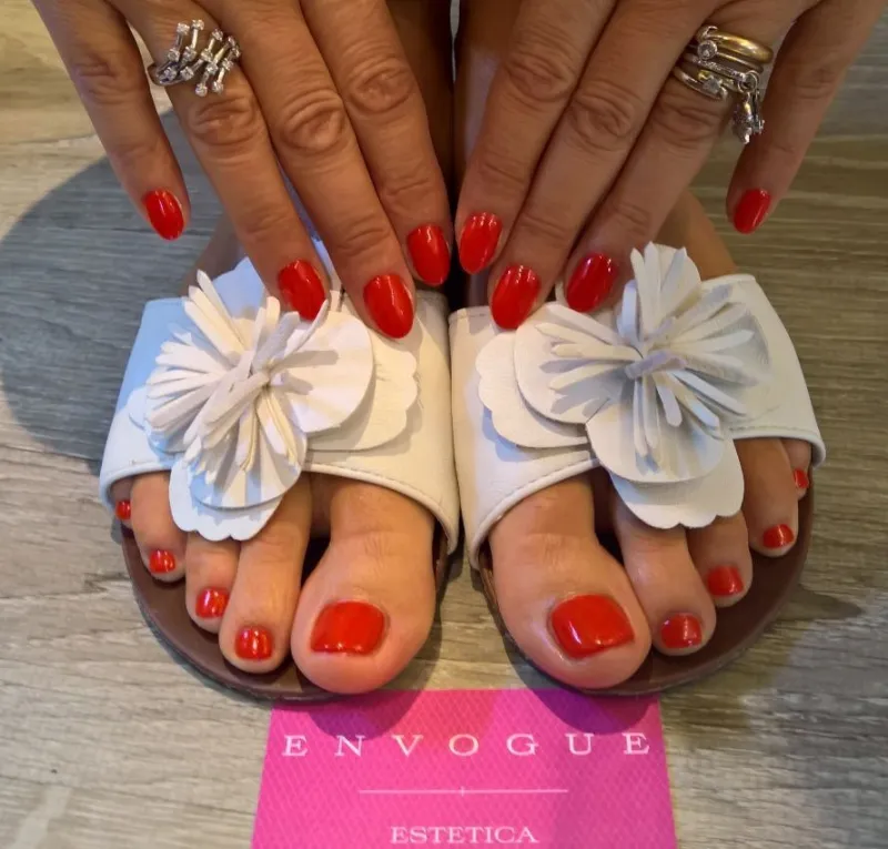 Smalto rosso sui piedi, sandali bianchi e biglietto Envogue