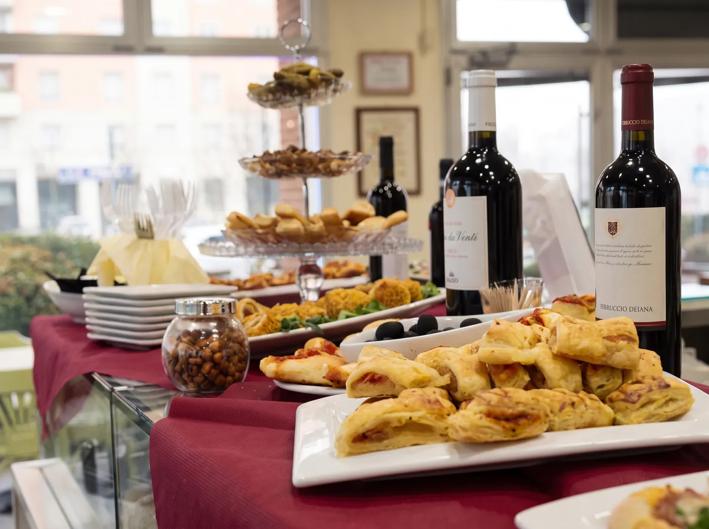 Il buffet dell'aperitivo: sfoglie salate su una tovaglia rossa.
