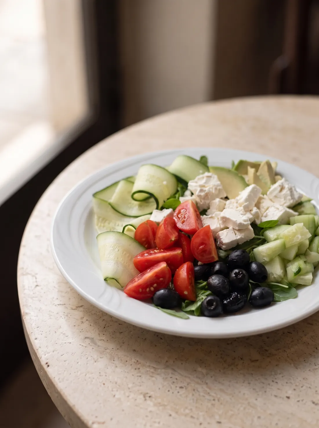 Un'insalata con pomodori, cetrioli, feta e olive nere.